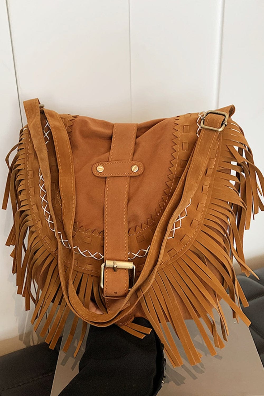 tribal style, fringed suede, buckled front with strap like a saddle bag, complete with crisscrossed stitching. 